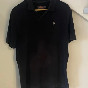Svart pikétröja från Morris, M - Klassisk svart pikétröja från Morris med korta ärmar och krage. Perfekt för en clean och stilren look. Äkta och i mycket bra skick 9,5/10 🍾
