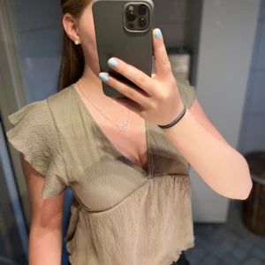 Beige blus med volangärm - Supersöt beige blus från lager 157 med v-ringning, volangärmar och knyt i ryggen. Luftigt tyg med lätt struktur och flowy passform. Perfekt till jeans eller kjol för en chill och trendig look. Endast använd ett par gånger så i jättefint skick. Storlek S