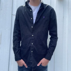 Svart Ralph Lauren skjorta- Stl XS, Slim fit - Svart Ralph lauren skjorta | S | Skick: 9,5/10 | modellen är 180cm | frakten sker på köparens bekostnad via Instabox eller PostNord! | Hör av dig vid frågor eller funderingar!
