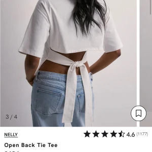 Vit croppad topp med öppen rygg Nelly - Superfin vit croppad topp från Nelly med öppen rygg och långa knytband som du knyter i midjan. T-shirten har korta ärmar och är gjord i mjuk bomull. Perfekt för dig som vill ha en trendig och unik look med coola detaljer.