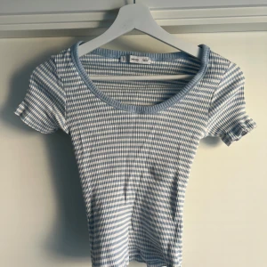 Blåvit rutig topp från MNG - Supersöt topp från MNG i blåvitt rutigt mönster. Modellen har korta ärmar med lätt volangkant och rundad halsringning med ribbad kant. Tunt och stretchigt material som sitter snyggt och bekvämt. Perfekt för dig som gillar en fräsch och trendig look.