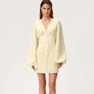 Adoore Florence dress - Intressekoll på florence dress pastel yellow storlek 40. Superfin ljusgul kortklänning med v-ringning, långa puffärmar och knappar framtill. Klänningen har ett subtilt blommönster och markerad midja som ger en snygg siluett. Perfekt för vår och sommar!