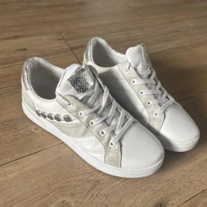 Vita Guess sneakers - Snygga vita sneakers från Guess med silvriga ormskinnsdetaljer✨Säljer då de tyvärr inte passade och var förstora… de har inte så många märkvärdiga defekter och är lite smutsiga, men jag tror det går bort om man tvättar dom lite🫶
