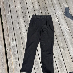 Svarta kostymbyxor från NeverDenim XS - Svarta kostymbyxor från NeverDenim i storlek XS. Byxorna har hög midja, raka ben och bälteshällor. 