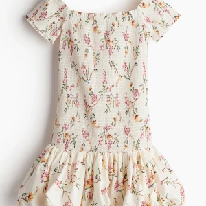 Blommig smockad k länning från hm  - Supersöt kortklänning från HM. Offshoulder med korta ärmar, smockad överdel och volangig kjol.