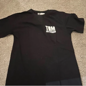Svart t-shirt Tom Millichamp - Svart t-shirt från Tom Millichamp med vit logga tryckt på bröstet. Köpt på hans hemsida, aldrig använt och har fortfarande lappen kvar!