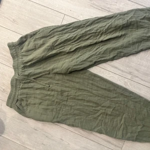 Olivgröna linnebyxor från Casual, strl 38 - Säljer ett par olivgröna linnebyxor från Casual i storlek 38. Byxorna har resår och snörning i midjan för skön passform och är tillverkade i ett lätt och luftigt linnematerial. Perfekta för chill dagar eller när du vill ha en avslappnad stil. Behövs bara strykas, Annars fint skick:)