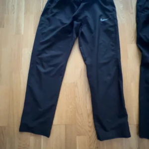 Nike dry pant byxor  - Två par svarta träningsbyxor från Nike med diskret logga på låret. Byxorna har elastisk midja och raka ben, tillverkade i ett lätt och smidigt syntetmaterial som passar perfekt för sport och aktivitet. Dessutom finns dom här inte att köpa längre o har fortfarande en hög efterfrågan pågrund av hur sköna o stilrena dom är! Säljer dom för 700 tillsammans eller 400kr st 