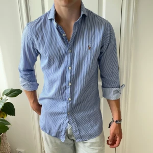Randig Ralph Lauren skjorta  - Blå vit Ralph Lauren skjorta, inga som helst defekter. Modellen bär 15, 32/33 vilket motsvarar ungefär S/M och modellen är 180,75 kg han själv. Kom med frågor!💛