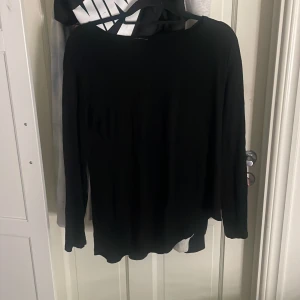 Svart långärmad tröja - En enkel svart långärmad tröja med rund halsringning. Tröjan har en rak passform och är tillverkad i ett mjukt och lätt material som passar perfekt till lager-på-lager eller som basplagg.