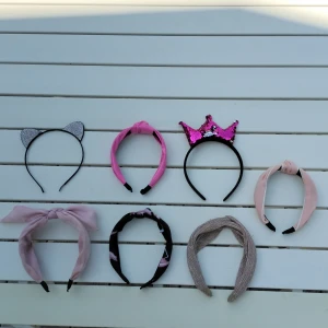 7-pack diadem  - Säljer ett set med sju diadem: ett svart diadem med glittriga kattöron, ett rosa diadem med knut, ett diadem med rosa paljettkrona, ett ljusrosa diadem med stor rosett, ett svart diadem med rosa mönster, ett beige diadem med metallicskimmer och ett ljusrosa diadem med knut. Perfekt för att variera din look!