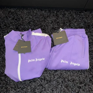 Lila Palm Angels tracksuit byxor - Säljer ett lila byxor från Palm Angels. Materialet är mjuk polyester och byxorna har resår i midjan.  OBS: BARA BYXOR 