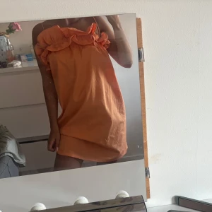 Orange kort klänning med volang - Superfin orange kortklänning med tunna axelband och volangdetalj upptill. Klänningen har en loose passform och är perfekt för varma dagar. Snygg och enkel att styla med sneakers eller sandaler, från Hm, inga defekter 