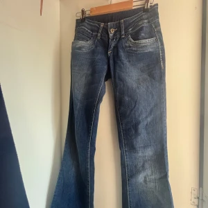 Blå bootcut jeans från Vero Moda - Snygga blå jeans från Vero Moda med bootcut passform. Lågmidjade Jeansen har klassisk femficksdesign, normal midja och är tillverkade i ett slitstarkt denimtyg. Perfekta för dig som gillar en tidlös och avslappnad look. 