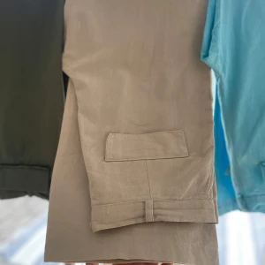 Beiga byxor  - Snygga beiga byxor med stora fickor fram. Byxorna har bälteshällor och en bakficka med lock.  Materialet är svalt och lätt samtidigt som det är väldigt fint på utsidan. (Oanvända. Står också strl 42 på insidan men det är mindre)