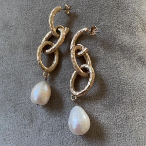 Chunky örhängen med pärlor i guld - Stora statement-örhängen med hamrade guldfärgade länkar och droppformade vita pärlor. Perfekta för att lyfta vilken outfit som helst med en cool och lyxig vibe.
