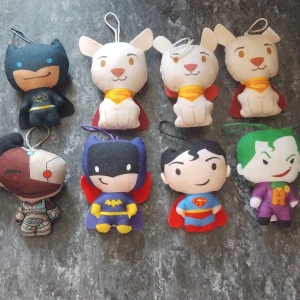 McDonald's lek saker (St 15kr) - Bilderna visar flera små mjukisdockor föreställande kända superhjältar och skurkar från DC Comics, som Batman, Superman, Batgirl, Cyborg, Joker och Krypto the Superdog. Dockorna är färgglada, har broderade detaljer och små öglor för upphängning. Perfekt för fans av superhjältar!