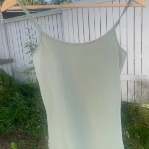 Ljusgrön linnetopp från Amisu - Enkel och stilren ljusgrön linnetopp från Amisu med smala, justerbara axelband. Toppen är ärmlös och har en rak passform, perfekt för varma dagar. Mjuk och skön känsla tack vare bomullsmaterialet. Snygg att matcha med jeans eller kjol.