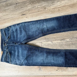 Mörkblå jeans från Giorgio 29 - Snygga mörkblå jeans från dondup med klassisk femficksdesign och kontrastsömmar. Jeansen har en skinny passform och coola detaljer på bakfickorna. Perfekta för dig som gillar en stilren look med lite tvättade effekter.