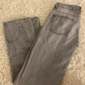 Grå raka jeans - Snygga grå jeans med klassisk rak passform och enkel bakficka. Byxorna har en stilren look och är tillverkade i ett mjukt jeanstyg som passar perfekt till en avslappnad outfit. De är dock fläckiga vet ej om det går bort i tvätt eller inte 