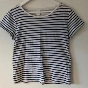 Svart/vit randig klassisk T-shirt! -  Klassisk vit t-shirt horisontella ränder och rund hals. T-shirten har korta ärmar och en avslappnad passform. Perfekt för en enkel och stilren look. Rak modell. Fint skick. Inga skador eller anmärkningar! 
