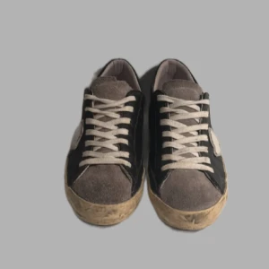 Philippe model - Snygga sneakers med svart skinn på sidorna, grå mocka på tån och plös samt vita detaljer och snörning. Sulan är beige med en sliten look. Skorna har en vit patch på sidan och rund tå. Perfekta för dig som gillar en avslappnad och trendig stil.