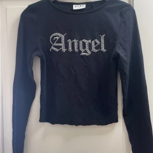 Svart långärmad topp med stenar  - Svart långärmad topp från STAY i storlek S med stenar på bröstet där det står 'Angel'. Tunn och mjuk bomullskvalitet. Passformen är normal/tajt och har en klassisk rund hals. Det är bara att skriva om du har frågor. I nytt skick då den knappt använts🤗finns inga defekter heller❣️