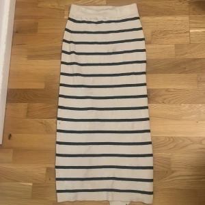 Vit och svart randig långkjol H&M XS - Säljer en långkjol från H&M i storlek XS. Kjolen är vit med svarta horisontella ränder och har en slits bak för extra rörelsefrihet. Materialet är mjuk manchester med tydlig struktur. Perfekt för dig som gillar klassisk stil med en twist.