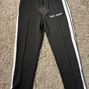 Palm Angels svarta trackpants med vit stripe - Svarta trackpants från Palm Angels använd ett par gånger men ingen märkning av användning om du har frågor de bara och fråga tröjan som passar till de här byxorna finns i min profil 