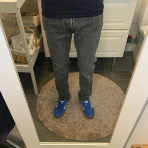 Grå Jack n Jones jeans - Säljer ett par grå jeans med klassisk femficksdesign och raka ben. Jeansen har en snygg mörkgrå tvätt och är tillverkade i slitstarkt bomullsmaterial. Passformen är straight och midjan är normal. Perfekta för dig som gillar en clean och tidlös look.