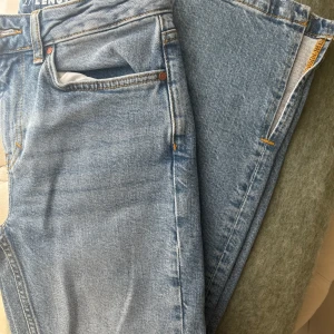 Ljusblå jeans från NA-KD, split hem - Säljer ett par ljusblå jeans från bikbok med split vid benslut. Jättefina & aldrig använda pga fel storlek 