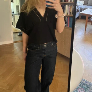 Svart blus med spetsdetaljer - Svart blus med v-ringning och fina spetsdetaljer längs halsringning. 