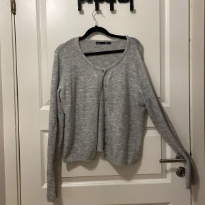 Grå kofta från 157 med knappar - Mysig grå kofta från 157 i storlek M. Den har rund halsringning, långa ärmar och knäppning framtill med små knappar. Materialet är stickat och känns mjukt mot huden, perfekt för lager-på-lager under kyliga dagar.