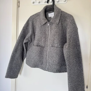 Grå teddyjacka från VILA, storlek 38 - Säljer en grå teddyjacka från VILA i storlek 38. Jackan har en rak, boxig passform, dragkedja framtill och två stora fickor. Materialet är mjukt och fluffigt, perfekt för kyliga dagar. Enkel krage och långärmad modell som ger en chill vibe. Liten i storlek. Passar Xs/S