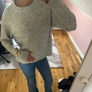 Grå stickad tröja med rund hals - Mysig grå stickad tröja med rund hals och långa ärmar. Tröjan har en enkel och clean look med ribbade muddar vid ärmslut och nederkant. Perfekt att slänga på sig när det är lite kyligt ute. Passar dig som gillar en chill och stilren vibe.