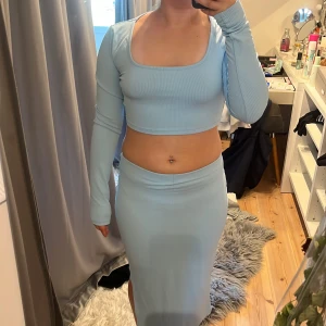 Ljusblå ribbad långkjol med tillhörande topp  - Säljer en ljusblå, ribbad långkjol med tillhörande topp som har en  tight passform. Settet är enkelt  och ger en stilren look, med mjukt stretchigt material som sitter snyggt mot kroppen. Perfekt för dig som gillar minimalistisk och fräsch stil.💕