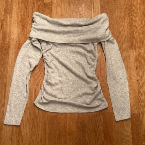 Grå offshoulder långärmad tröja Amisu - Säljer en ljusgrå långärmad tröja från Amisu i storlek XS. Tröjan har en snygg offshoulder-design med bred krage som vilar över axlarna. Mjuk och stretchig bomullsmix som sitter slim och framhäver figuren ❤️