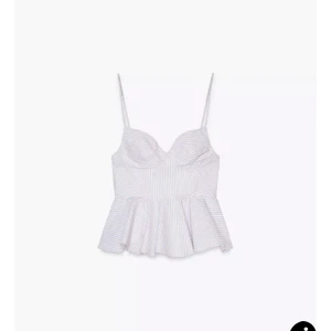 Vit randig linnetopp med volang - Supersöt vit linnetopp med tunna pastellfärgade ränder och smala axelband. Perfekt för varma dagar och lätt att matcha med jeans eller kjol.