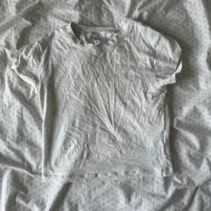 Ljusgrå basic t-shirt från hm - En enkel och stilren ljusgrå t-shirt från hm i storlek M. Modellen är klassisk med rund hals och korta ärmar, perfekt för en chill och clean look. Materialet är mjuk bomull som känns skönt mot huden. Passformen är normal och t-shirten är helt utan mönster eller detaljer.