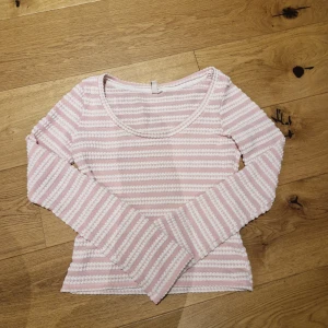 Rosa och vit randig tröja från Nelly - Säljer en söt långärmad topp från Nelly i storlek S. Den är endast använd ca 2 ggr. Den är lite stor i storlekten, mer som M.