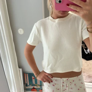 Vit croppad stickad topp - Säljer en enkel och stilren vit croppad stickad topp med korta ärmar och rund halsringning. Storlek L men passar mig som brukar bära S. Passar snyggt till både jeans och kjol💌