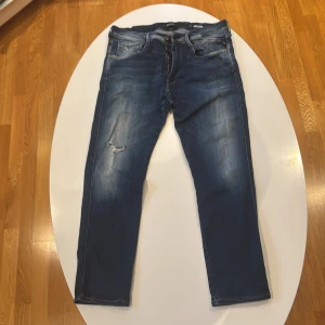 Replay Anbass blå jeans herr 36/30 - Mörkblå Replay anbass jeans med snyggt tvättad look och lätt slitning vid knät för den där perfekta, avslappnade stilen. Skön stretch som gör att de sitter som en smäck men ändå är bekväma hela dagen.
