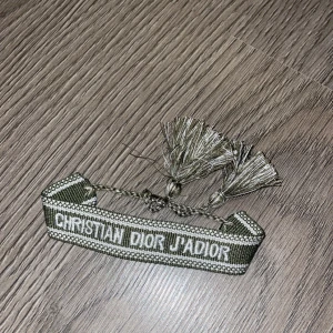 Dior armband - Mörkgrönt Christian Dior armband med justerbara tofsar. Kostar 130 kr och inge andra prisförslag eller förhandlingar.