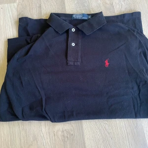 Svart pikétröja från Polo Ralph Lauren - Säljer nu min svarta polo Ralph lauren pikétröja, den är använd med omsorg och inga tydliga märken på användning, stilren och klassik, fungerar perfekt i vardagen men även om man vill klä upp sig lite. Vid frågor kontakta mig vänliga hälsningar!