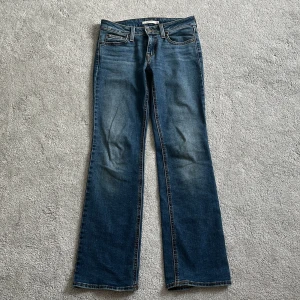 Levi's Superlow Bootcut jeans blå - Snygga blå Levi's Superlow Bootcut jeans i klassisk denim. Låg midja och bootcut-ben ger en retro vibe. Jeansen har fem fickor, dragkedja och knapp framtill samt ikonisk Levi's patch bak. Perfekta för dig som gillar en avslappnad men ändå stilren look. Köpte dem för ca 1000 kr, och dem är i bra skick. Passar mig som är 160 och har xs i storlek i vanliga fall. 