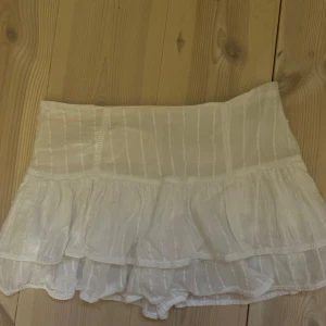 Vit volangkjol från Pull&Bear - Supersöt vit kortkjol från Pull&Bear med inbyggda shorts