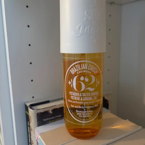 Sol de Janeiro Brazilian Crush 62 - Fräsch och söt kroppsspray från Sol de Janeiro med doft av pistage och salt karamell. Flaskan är genomskinlig med gul vätska och har ett stort vitt lock. Perfekt för dig som älskar gourmanddofter och vill dofta somrigt och unikt. Se bild hur mycket det är kvar 