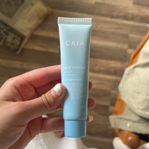 CAIA SOS Rescue Balm 25g - CAIA SOS Rescue Balm är en närande balm i ljusblå tub med sheasmör och vitamin E. Perfekt för torra partier i ansiktet, låser in fukt och mjukgör huden. Vegansk och dermatologiskt testad, tillverkad i Korea. Smidig att ha med i väskan. Oanvänd 