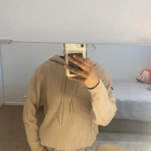 Beige ribbad hoodie med huva - Beige ribbad hoodie med huva och dragsnören från Lager 157 i storlek S. Tröjan har lång ärm och är i ett mjukt stickat material. Den är i väldigt bra skick bortsett från det i bild nummer 4