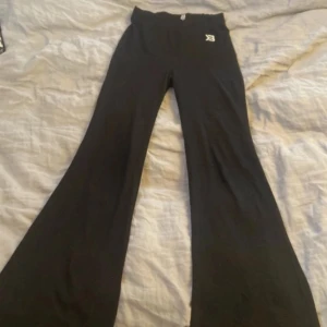 Svarta bootcut byxor Better Bodies S - Svarta bootcut byxor från Better Bodies i stretchigt material. Hög midja och utsvängda ben ger en snygg siluett. Perfekta för dig som gillar sportig och trendig stil. Diskret logga framtill och tydlig logga bak på linningen.